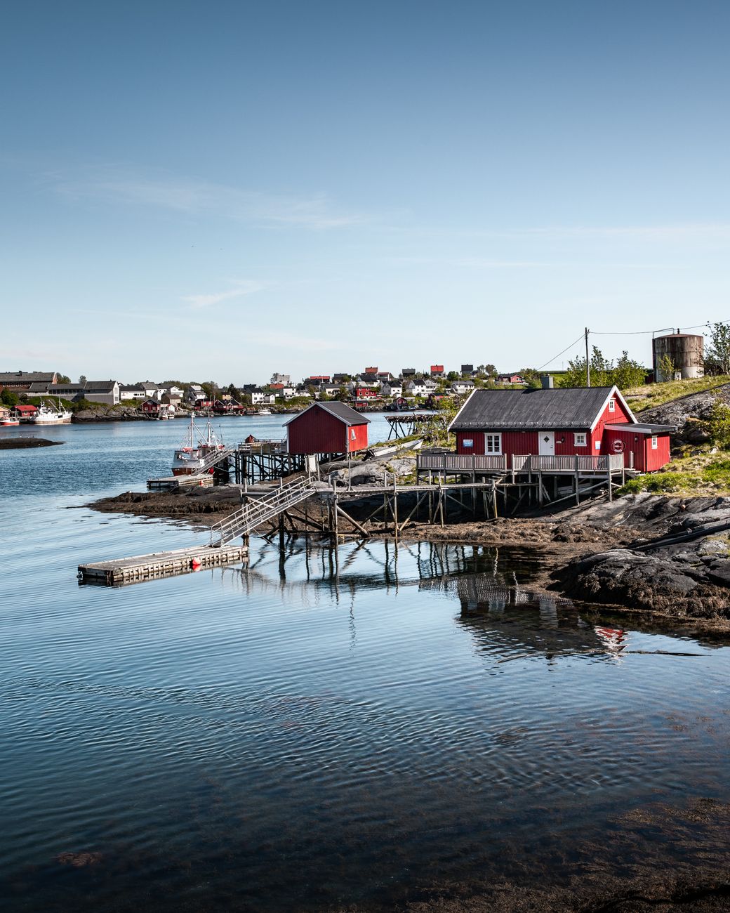 Red wooden cottage overlooking deep calm fjord waters